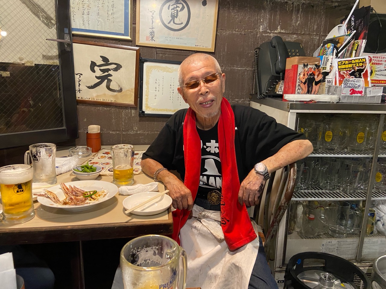 店内で赤いタオルを首にかけてくつろぐ村田善則マスター